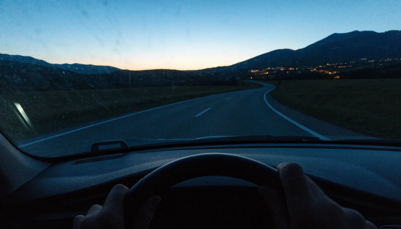 Leere Landstraße in Österreich in der Abenddämmerung mit Hügeln am Horizont