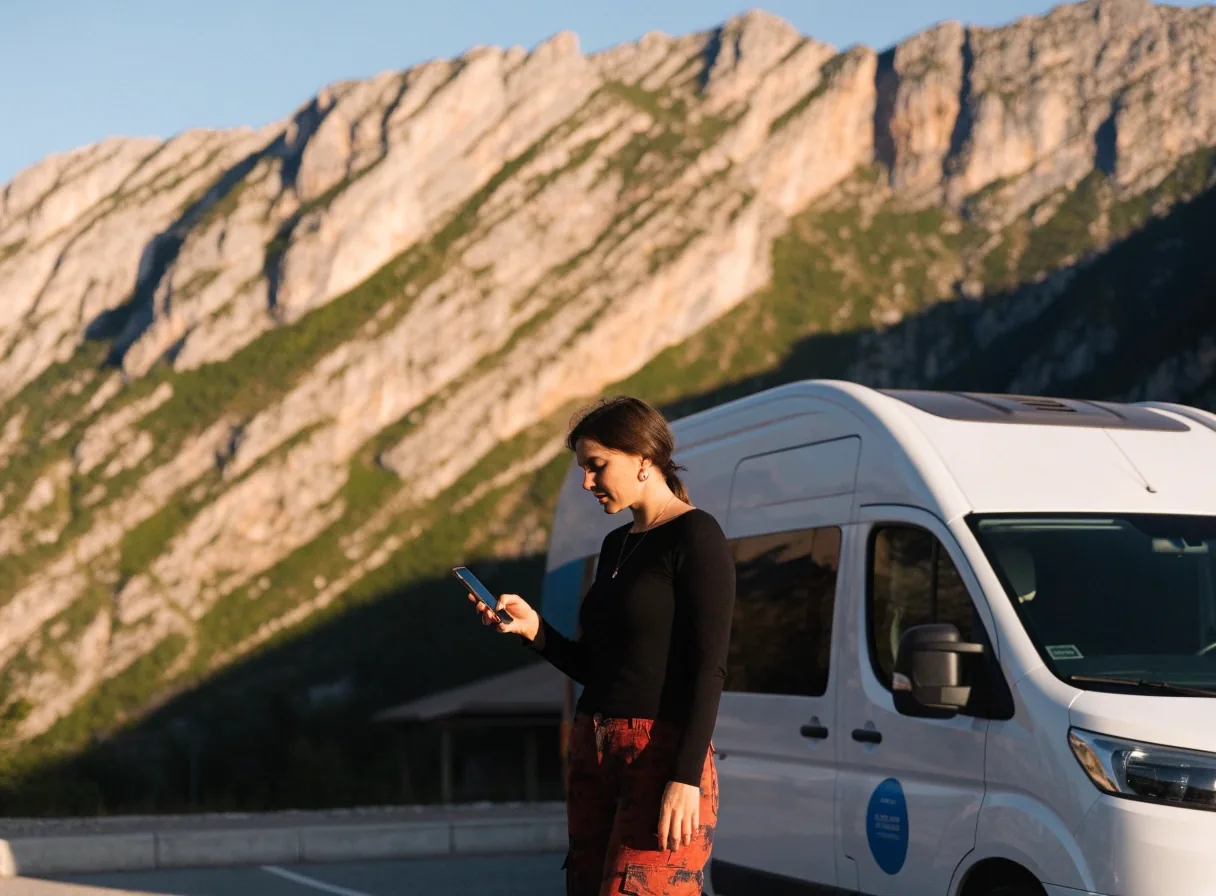 Frau plant am Rastplatz vor dem Alpenpanorama ihre Fahrt mit Straßenatlas
